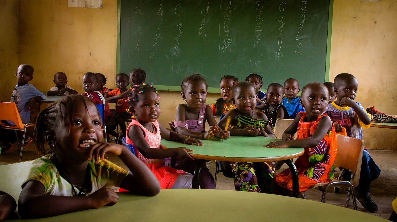 Niños y niñas atienden, sentados en sus mesas, una explicación en la escuela montada también gracias al proyecto