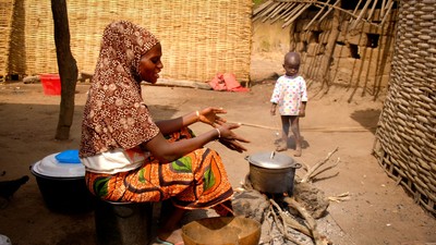 Una mujer cocina a la puerta de su choza
