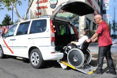 Un taxista ayuda a una mujer a acceder, montada en su silla de ruedas, en un vehículo adaptado (Eurotaxi)