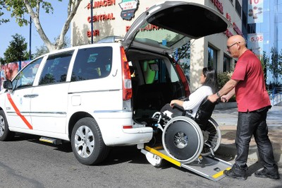 Un taxista ayuda a una mujer a acceder, montada en su silla de ruedas, en un vehículo adaptado (Eurotaxi)