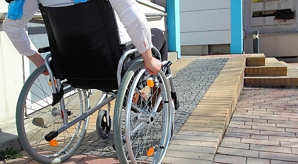 Una persona en silla de ruedas accede por una rampa a un centro sanitario