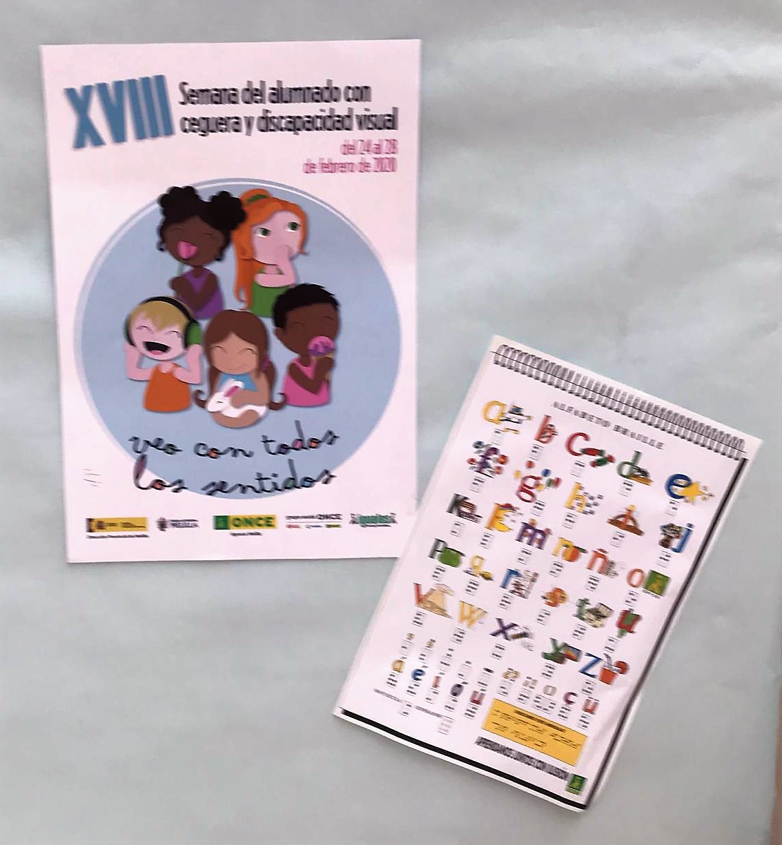 El cartel de las Jornadas (a la izquierda) junto a un ejemplar explicativo visualmente del alfabeto braille