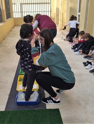 Las instructoras sitúan a dos niñas para realizar el recorrido a ciegas 'Paso a Paso'
