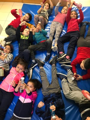 un grupo de niños tumbados sobre una colchoneta experimentan con las botellas 'sensitivas'