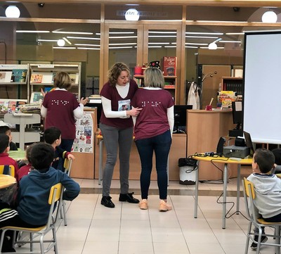 Una de las instructoras explica a los pequeños cómo otra compañera lleva su nombrado grabado con puntos braille en su camiseta 