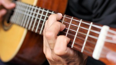 Primer plano de un músico tocando la guitarra española