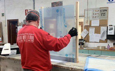 Un operario instala una mampara en un mostrador de atención al público de unas dependencias
