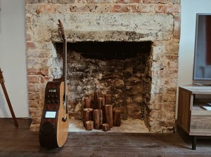Guitarra apoyada junto a una chimenea