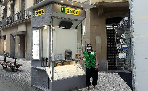 Una vendedora de la ONCE de San Sebastián posa ante su kiosco provista de su mascarilla y guantes