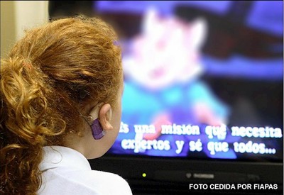 Joven sorda frente a una pantalla con subtítulos
