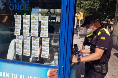 Un guardia urbano de Barcelona compra un cupón, en un quiosco de la ONCE, a primera hora del lunes 15