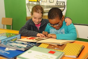 Alumnos ciegos en el aula manejando libros adaptados