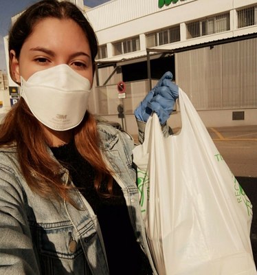 Una voluntaria de Fundación ONCE reparte, provista de su mascarilla, una de sus bolsas de comida para vulnerables