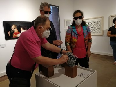 Un visitante reconoce al tacto una obra escultórica en la inauguración de la exposición en Mula