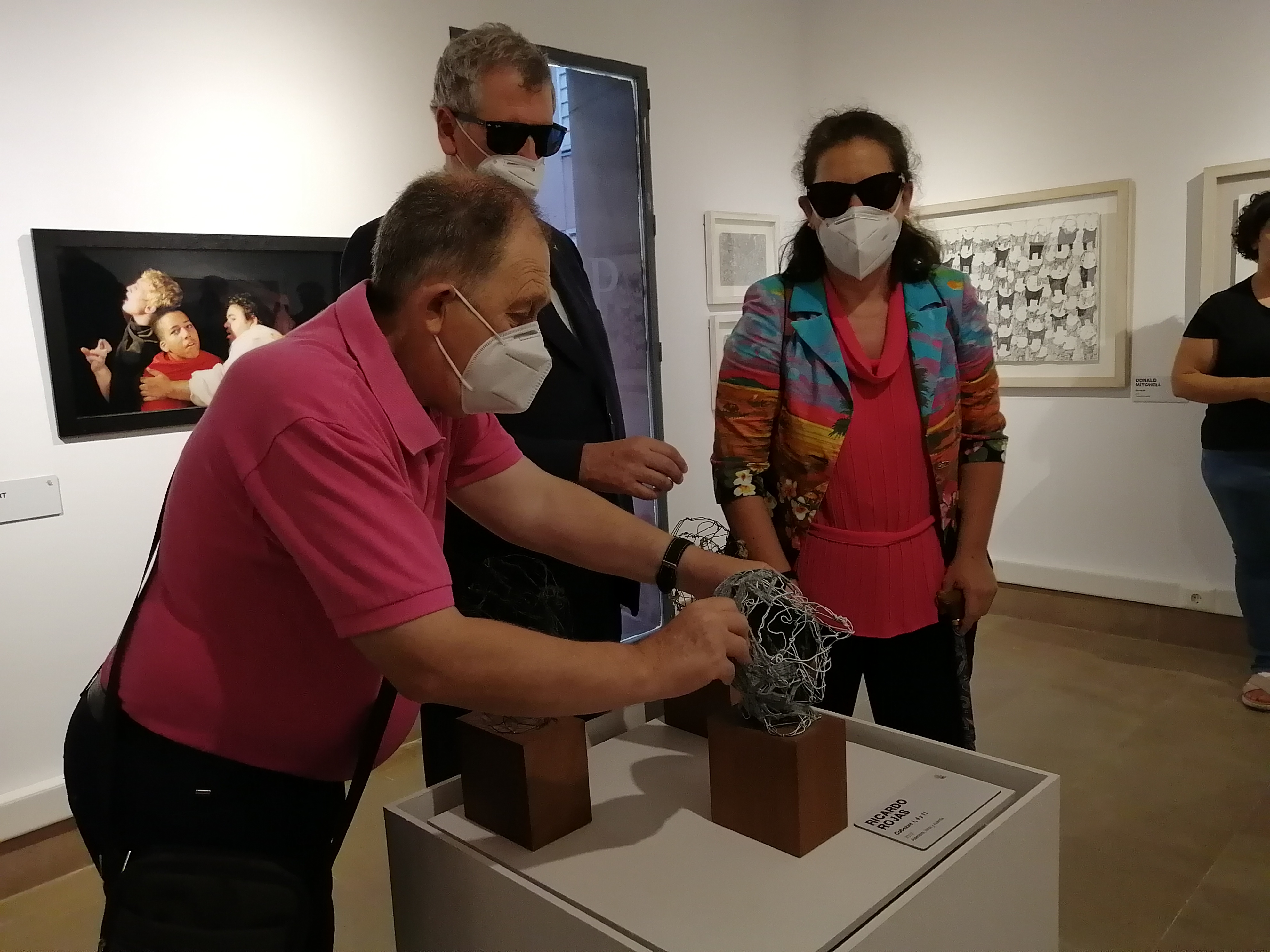 Un visitante reconoce al tacto una obra escultórica en la inauguración de la exposición en Mula