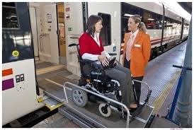 Una agente del servicio Renfe Atendo asiste a una viajera en silla de ruedas al llegar a su estación de destino