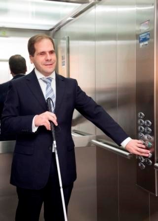 Una persona ciega toca una botonadura de un ascensor para movilizarlo