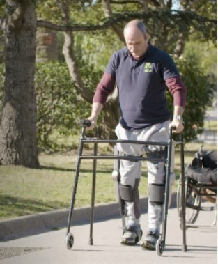 Una persona con movilidad reducida pasea por un parque ayudado por el exoesqueleto creado por la empresa barcelonesa