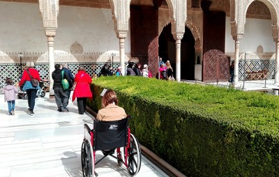 Una persona en silla de ruedas, junto a otros visitantes, en la Alhambra granadina