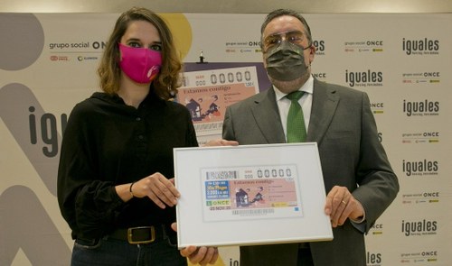 Noelia Vera y Miguel Carballeda muestran el cupón dedicado al Día Internacional de la Eliminación de la Violencia contra la Mujer con el lema "Estamos contigo"