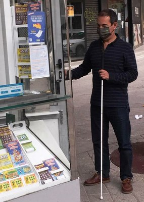 Persona ciega junto a un kiosco de la ONCE