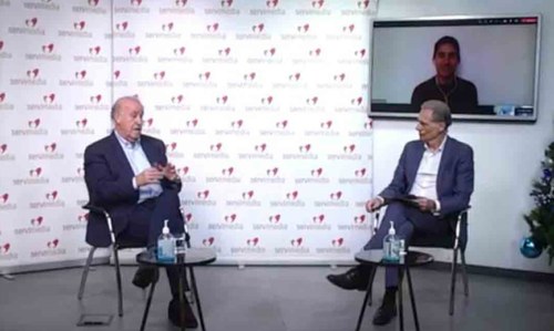 Momento del encuentro entre Vicente del Bosque, junto a José Manuel González Huesa, director de Servimedia y moderador del encuentro. En la pantalla, Adolfo Acosta.