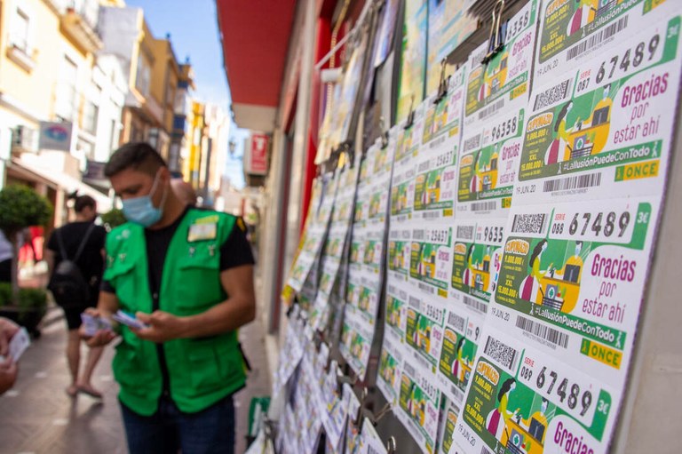 Primer plano de cupones dedicados a los héroes de la pandemia con un vendedor de la ONCE al fondo