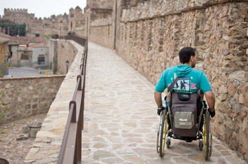 Joven en silla de ruedas paseando por la monumental muralla de Ávila