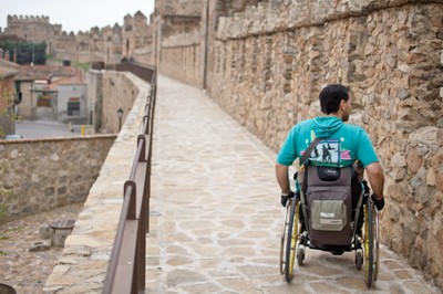 Joven en silla de ruedas paseando por la monumental muralla de Ávila