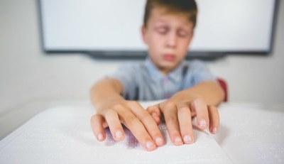 Escolar ciego leyendo un texto en braille
