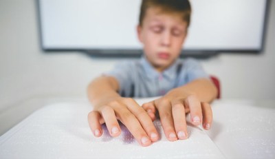 Escolar ciego leyendo un texto en braille