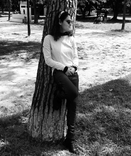 Catiana posa en un parque recostada en el tronco de un árbol (imagen en blanco y negro) 