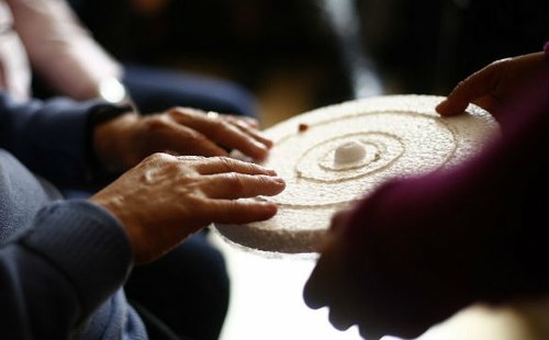 Manos tocando una reproducción en relieve del sistema solar