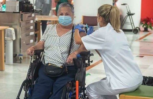 Mujer en silla de ruedas recibiendo la vacuna