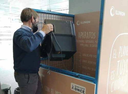 Un trabajador de ILUNION deposita un aparato electrónico en uno de los contenedores instalados en la sede 