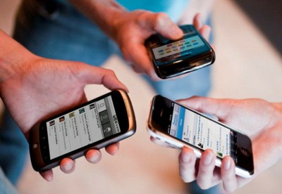 Tres personas manejan sus teléfonos móviles