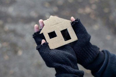 Manos sujetando una casita realizada en cartón