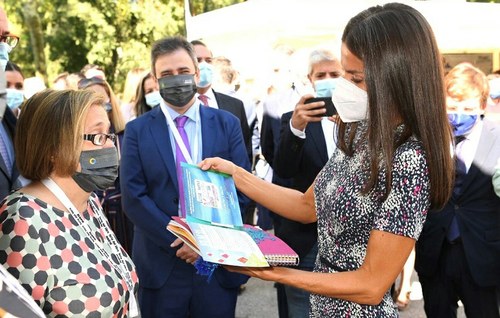 Imelda Fernández muestra a la reina el cupón dedicado a la FLM y uno de los libros infantiles adaptados