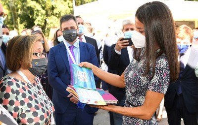 Imelda Fernández muestra a la reina el cupón dedicado a la FLM y uno de los libros infantiles adaptados