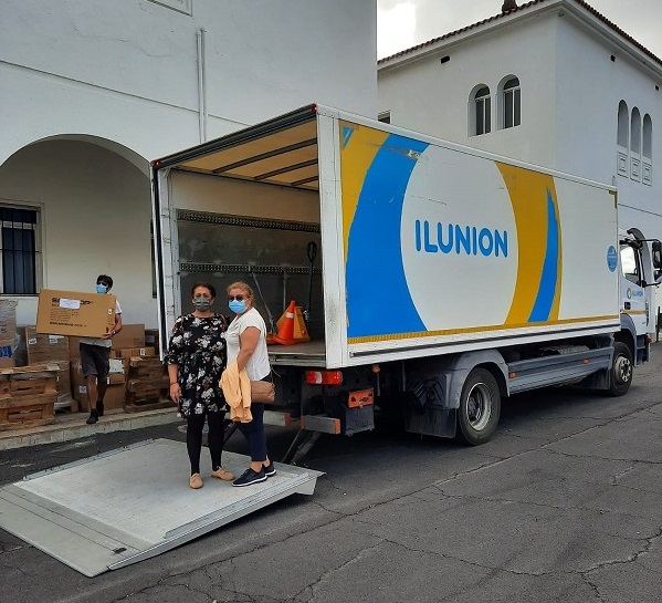 Esmeralda,a la izda., y Juana junto a uno de los camiones de Ilunion que realizan en reparto de gafas y gorras