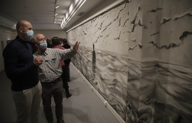 Dos visitantes analizan los detalles del mural