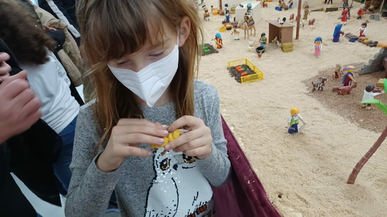 Una niña afiliada toca una de las figuritas del Belén de Playmobil