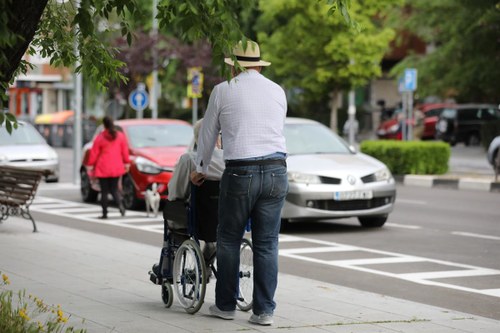 Una persona mayor empuja a otra sentada en una silla de ruedas