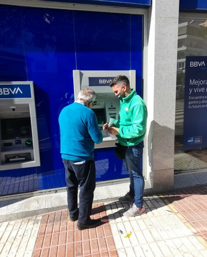 Juanma Larrubia Decosa ayuda a personas mayores en sus gestiones con el banco al lado de su punto de venta