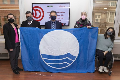 Foto de familia de los representantes de Fundación ONCE y Asociación de Educación Ambiental y del Consumidor con una bandera azul