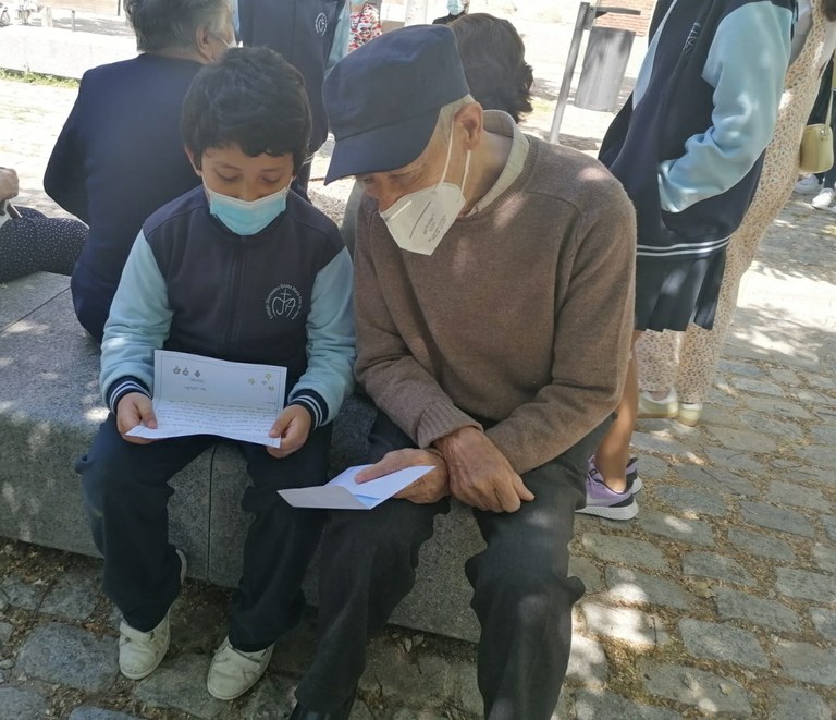 Un anciano escucha atentamente  la carta que le lee uno de los escolares