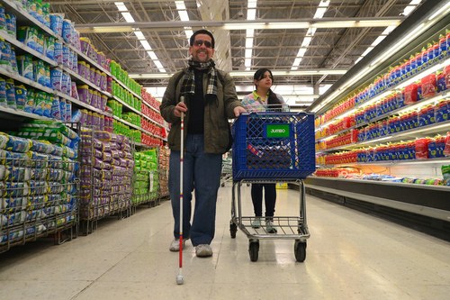 Una persona ciega realizando una compra en un supermercado