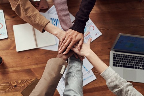 Cuatro manos juntas sobre una mesa de reuniones