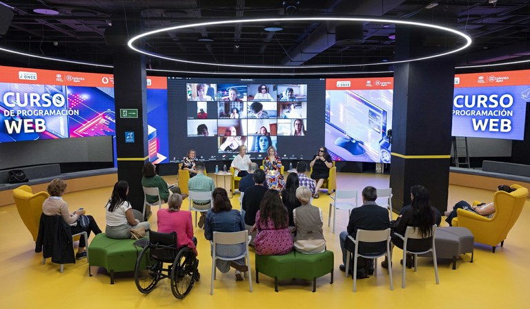 Panorámica del acto de presentación en el hub de X Talento Digital con asistencia de responsables y alumnos y alumnas, algunos presenciales y otros conectados on line, como se observa en la gran pantalla del fondo