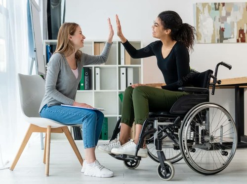 Dos jóvenes, una de ella en silla de ruedas, se dan la mano